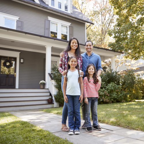 Family standing smiling in front of their house